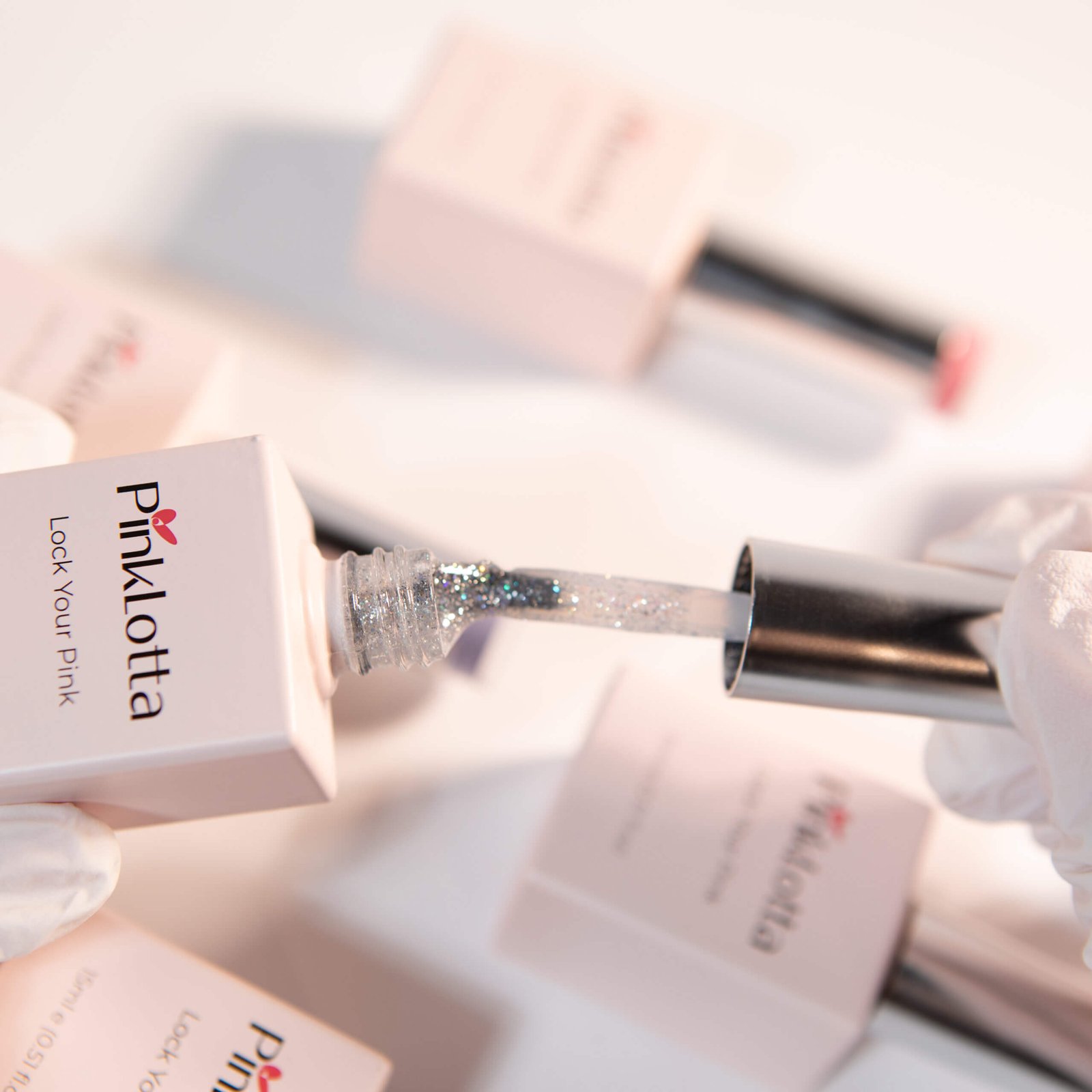 PinkLotta GH804 Dewlight Gel Polish, UV Gel—silver micro-glitter on brush, close-up with soft pink background.