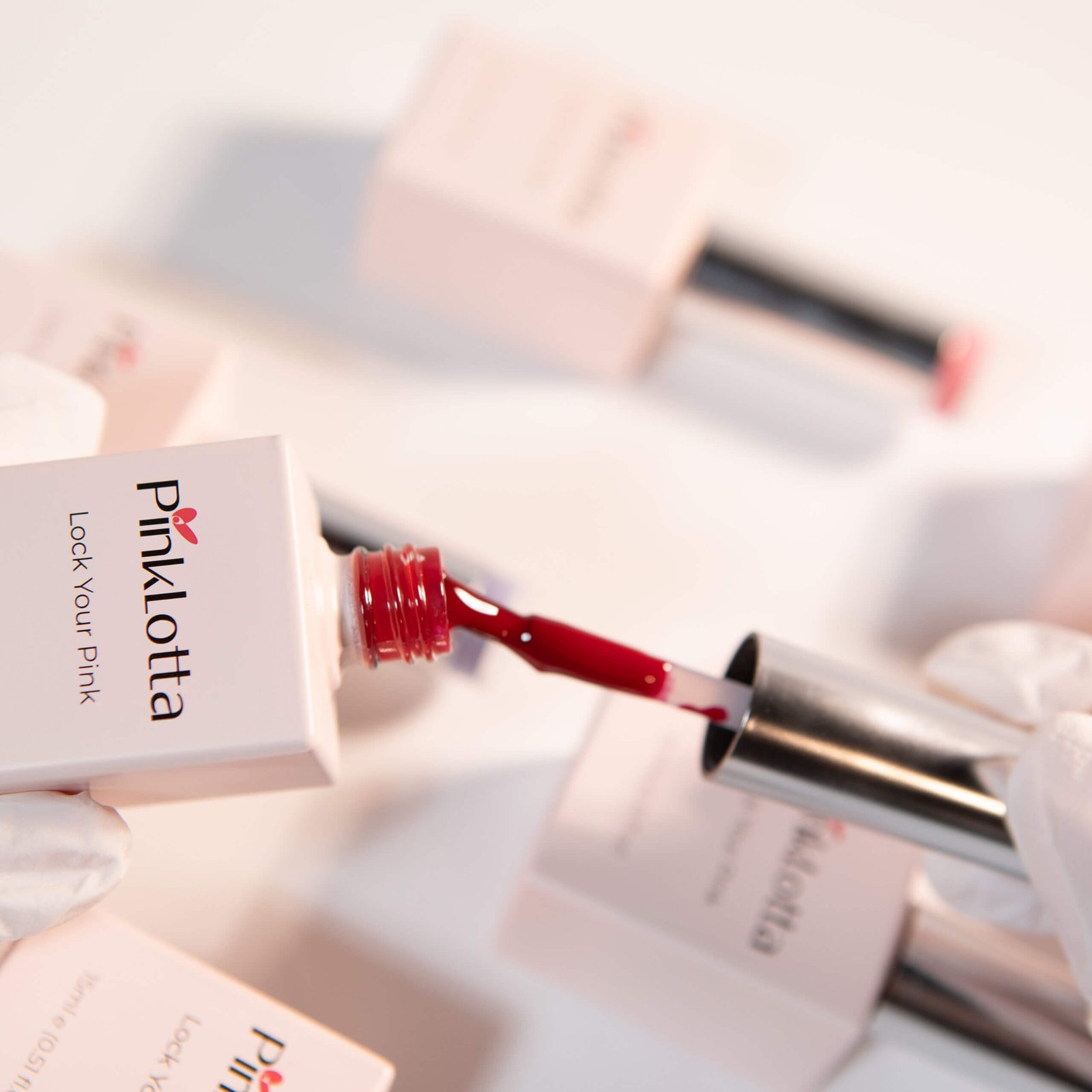PinkLotta SH104 Cherry Red Gel Polish, UV Gel—vivid ruby red on brush, macro shot, pink background.